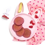 婴孩或小孩的桃红色兔宝宝用桃红色薄煎饼，莓和鲕梨坐与一个白色叉子的桃红色餐巾用来使用。