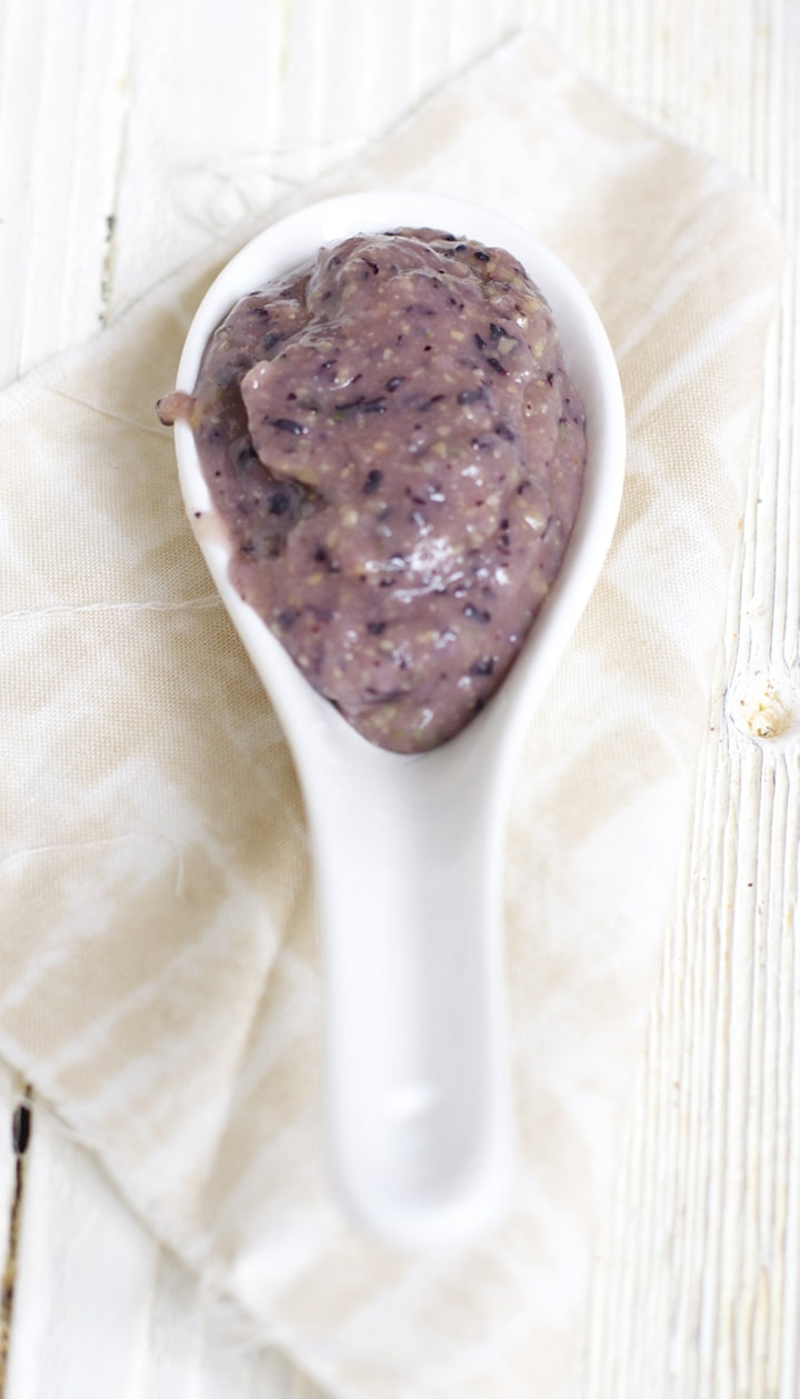 基于餐巾的匙子满是蓝莓鸡豆婴儿食物泥。