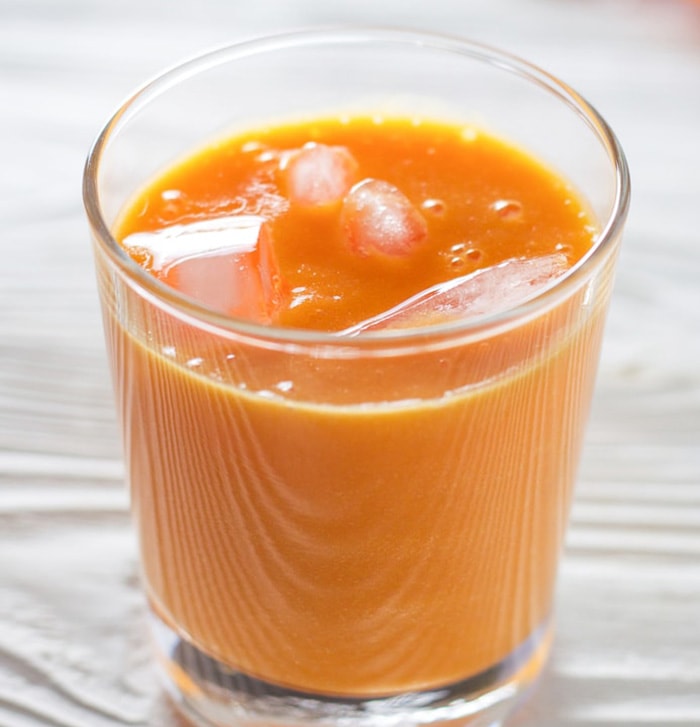 glass of carrot and orange juice with ice.