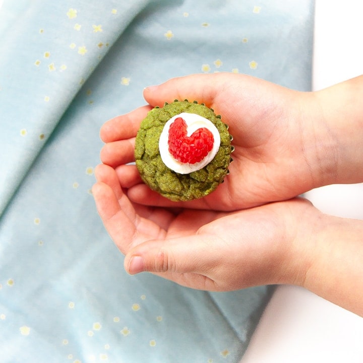 Small kids hands holding a grinch muffin.
