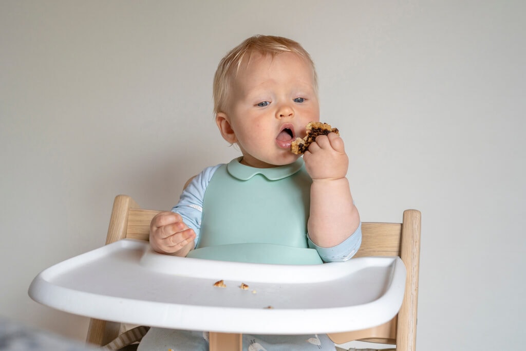 椅子上的婴儿用自己的手吃食物。