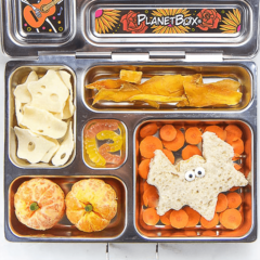 图像是一个开放式午餐盒，里面有健康的万圣节主题食物。