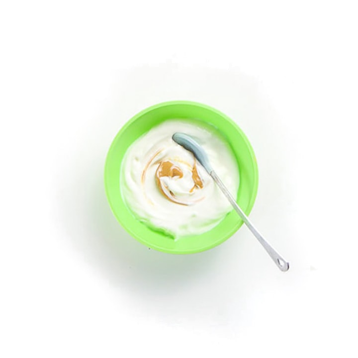 绿色婴孩碗用花生酱酸奶和漩涡。
