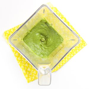 婴儿泥食谱 - 搅拌机坐在黄色的餐巾纸上。内部搅拌器是光滑的绿色泥