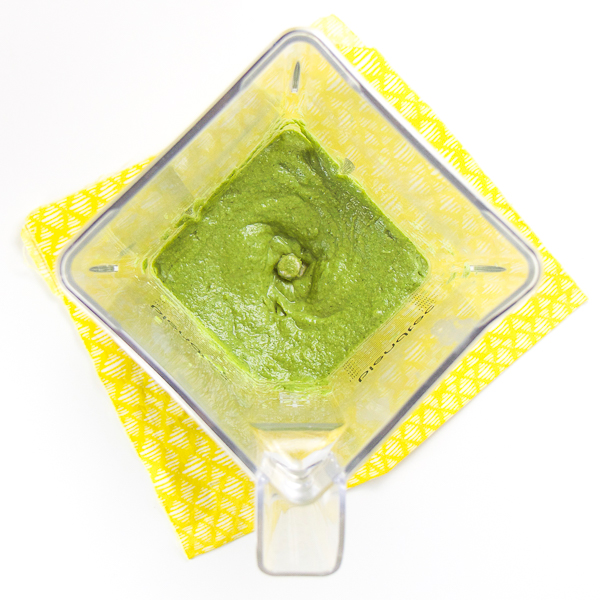 婴孩puree食谱 - 搅拌器坐在顶部黄色餐巾。搅拌机里面是一个光滑的绿色泥