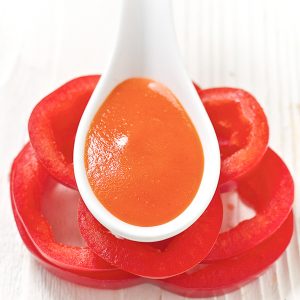 白汤匙放在一堆红辣椒片的顶部。汤匙里面有红辣椒婴儿食品食谱。