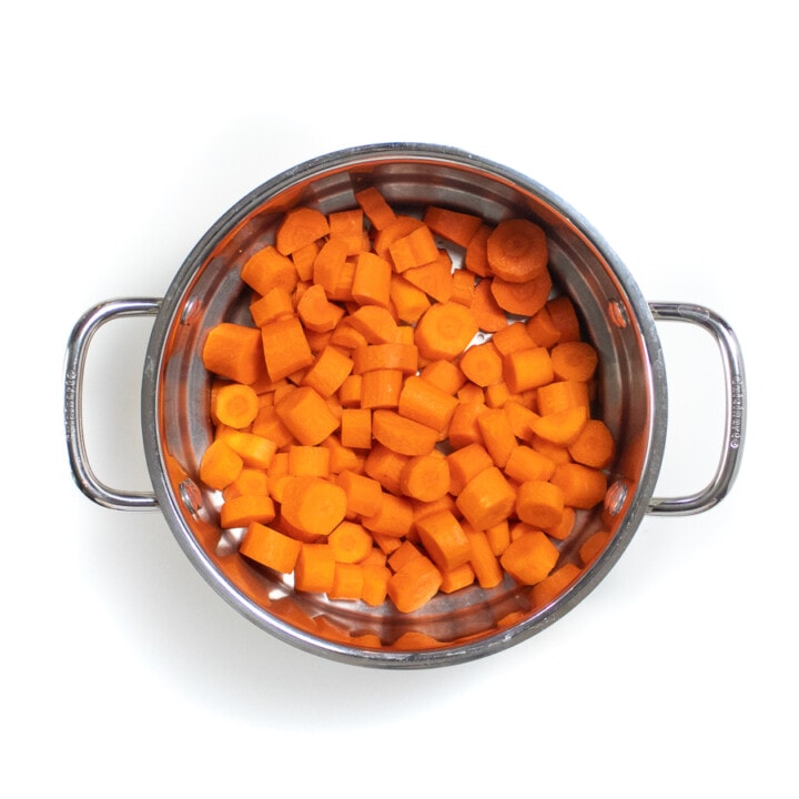 一个银色蒸锅篮，切成薄片的胡萝卜。