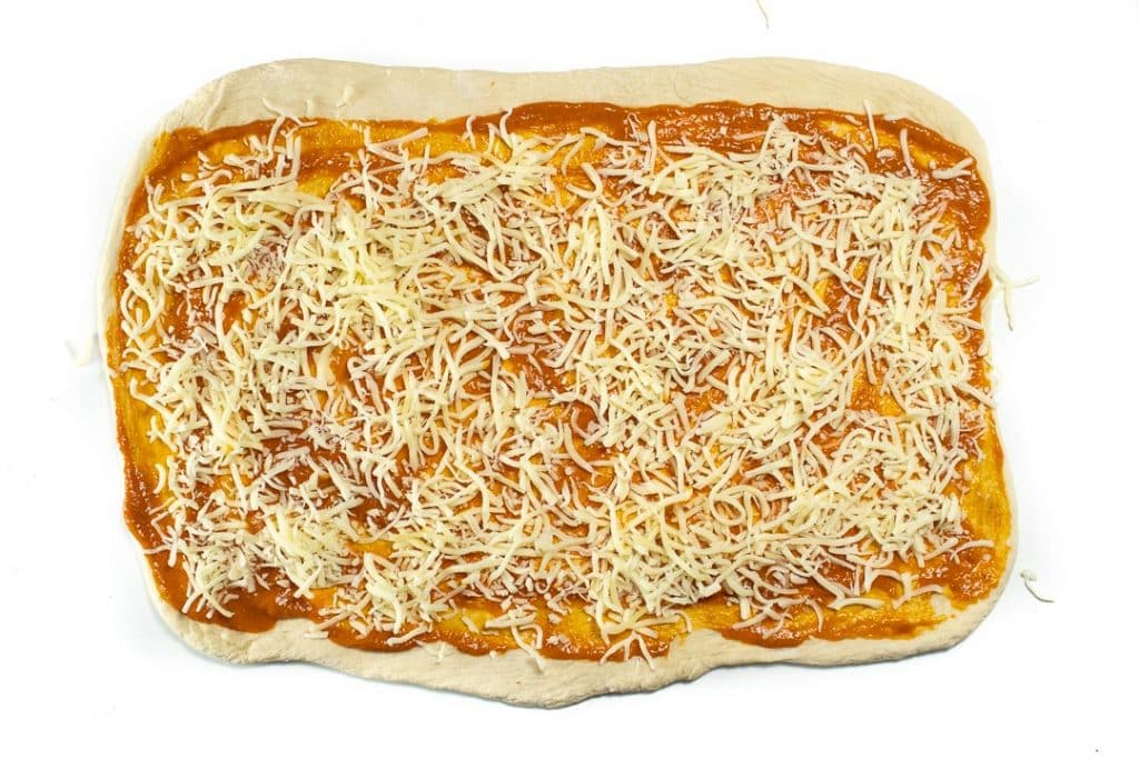 披萨面团在矩形中，带有隐藏的素食酱和奶酪。