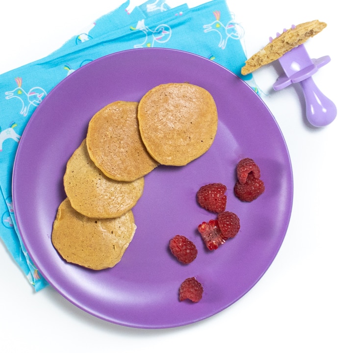 紫色盘子配香蕉煎饼和婴儿覆盆子碎片。