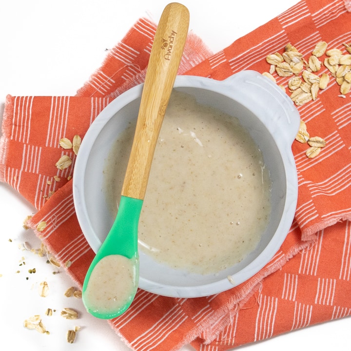 碗燕麦片，用于婴儿，勺子放在灰色碗的顶部。
