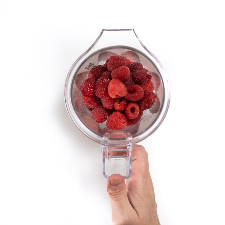 递拿着一个清楚的搅拌器用里面新鲜的莓