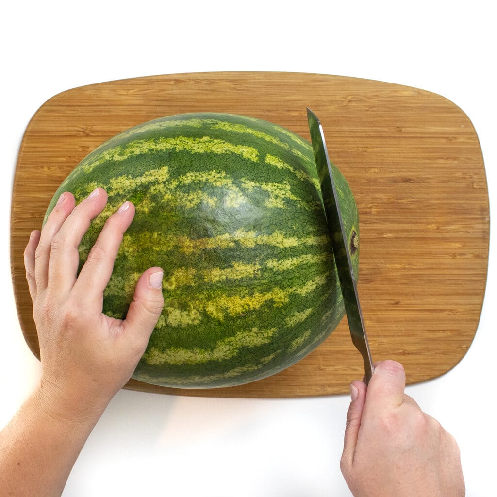 切菜板上的西瓜，双手切断一端。
