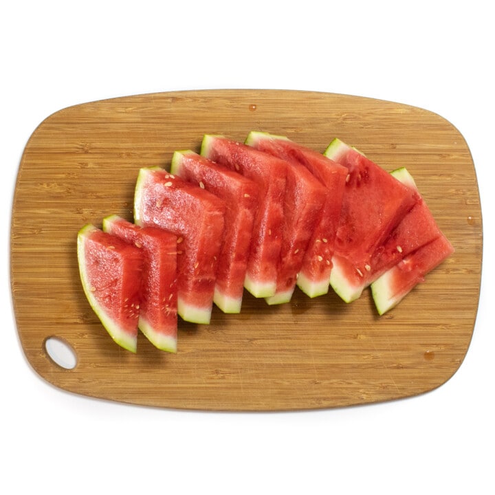 一个木制切菜板，上面放着切成薄片的西瓜。