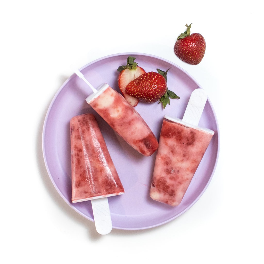 03草莓酸奶冰棍在紫色盘子上贴在背景的紫色盘子上。