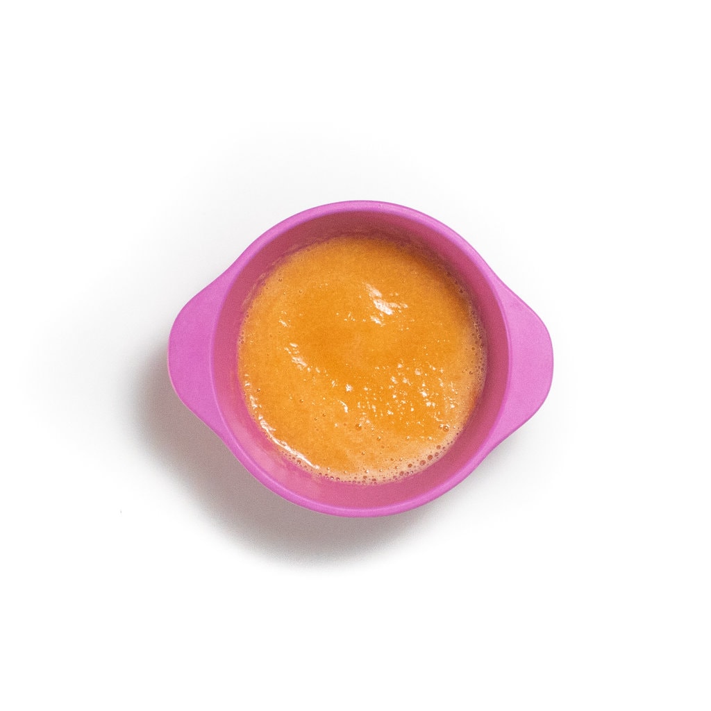 一个粉红色的婴儿碗，配有光滑的哈密瓜泥。