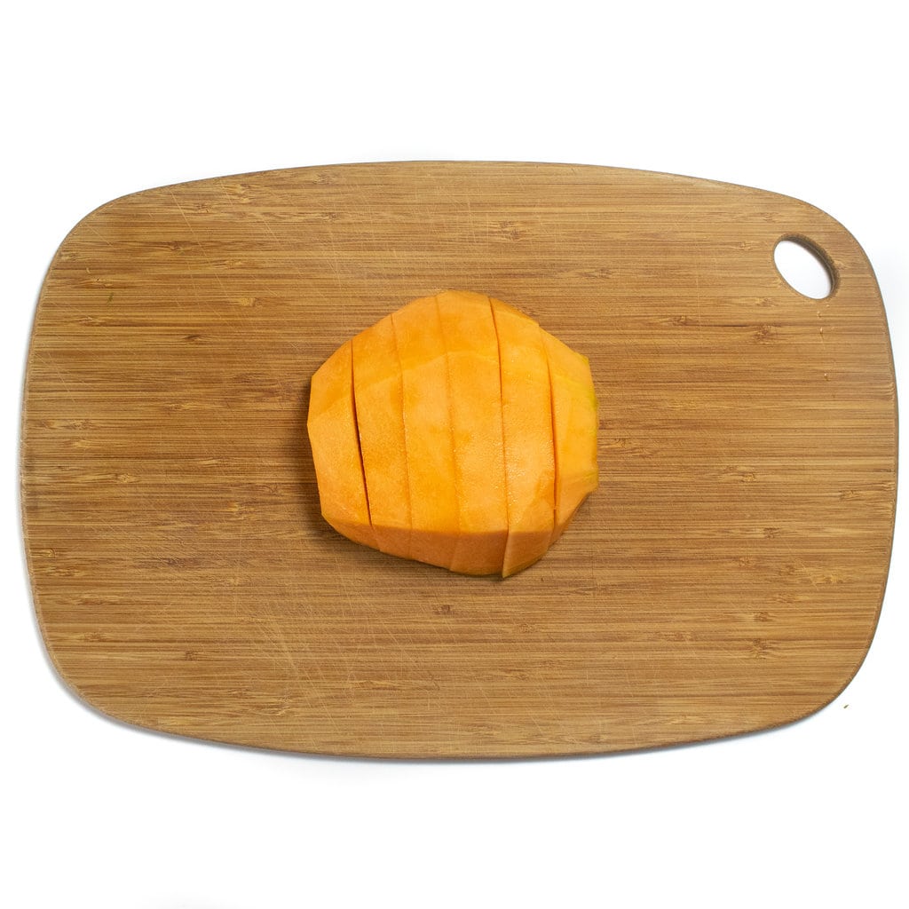 将哈密瓜切片固定在木制切菜板上，在客场背景下。