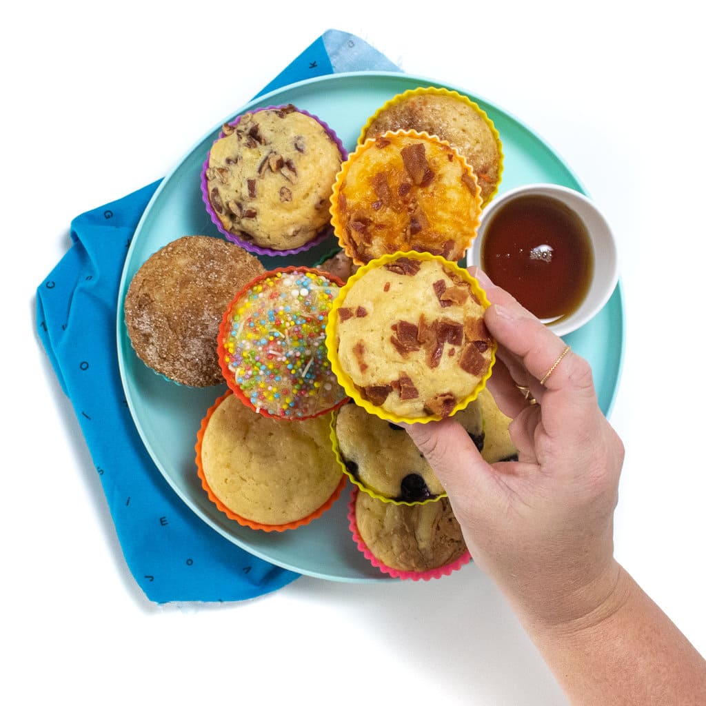 一个蓝色的孩子和蓝色的孩子餐巾一起玩，盘子上有煎饼松饼，带有各种浇头。