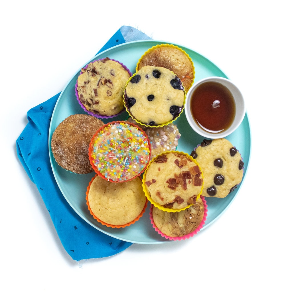 一个蓝色的孩子和蓝色的孩子餐巾一起玩，盘子上有煎饼松饼，带有各种浇头。