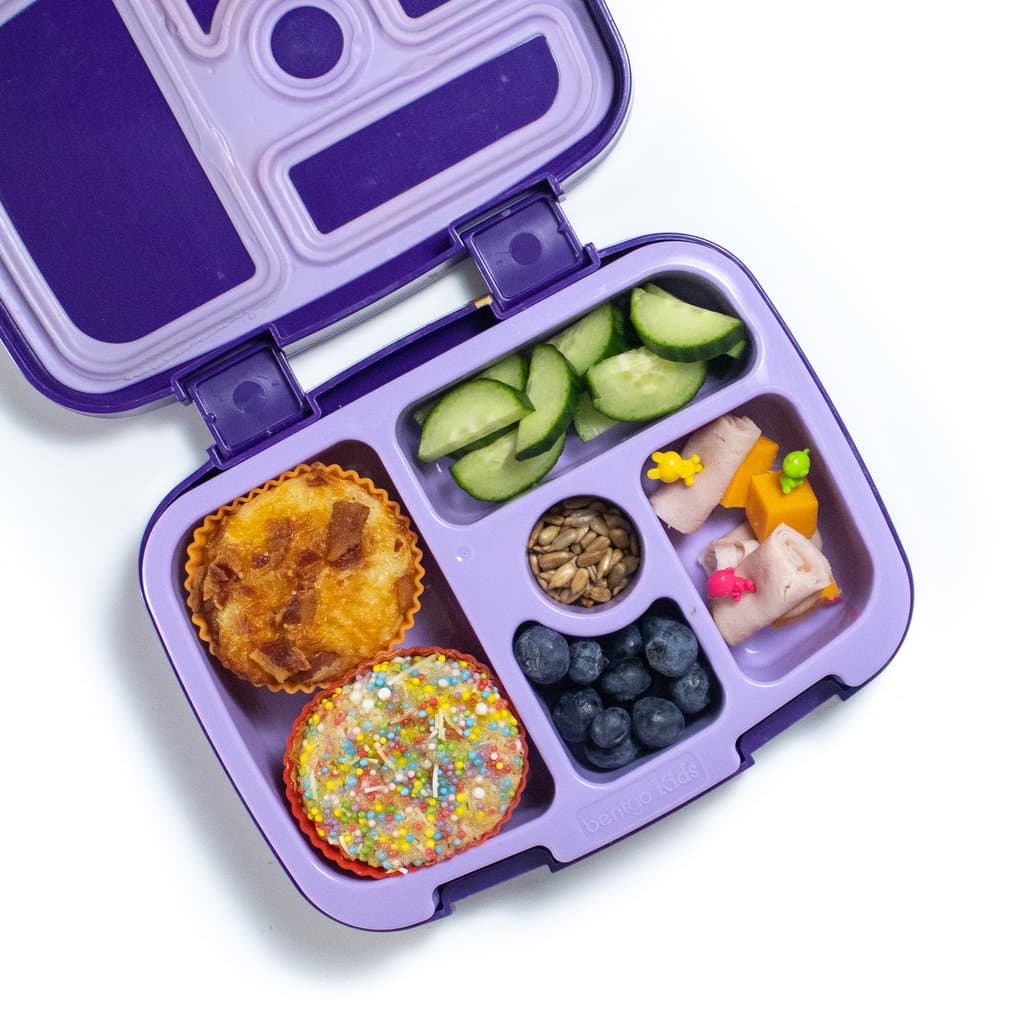 带有煎饼松饼的紫色午餐盒，带有两种不同的浇头，切成薄片，蓝莓和火鸡卷。