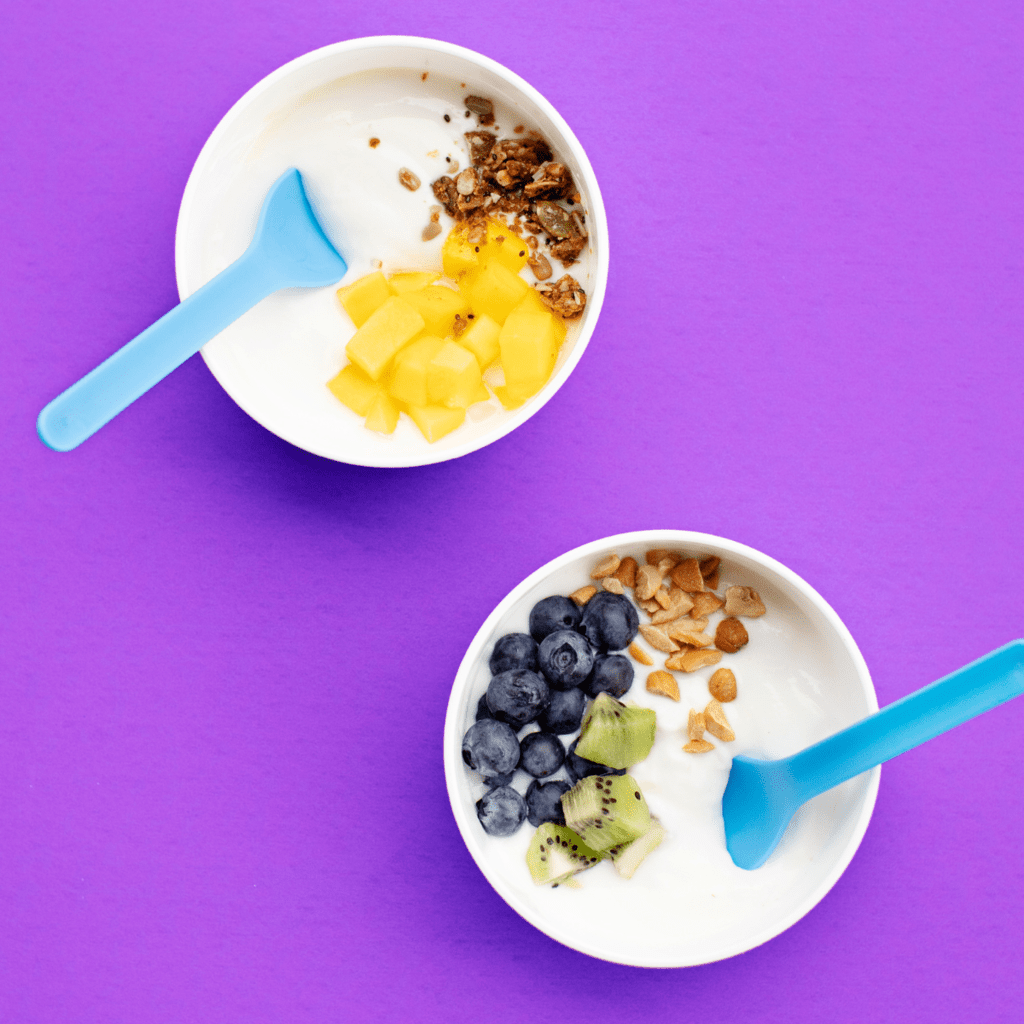 两个白色碗充满酸奶和紫色背景。