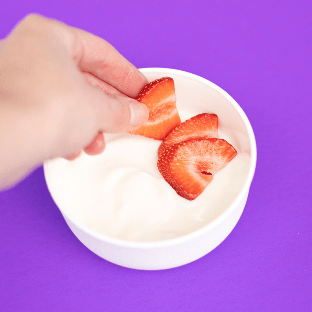 将草莓放入一碗酸奶中。
