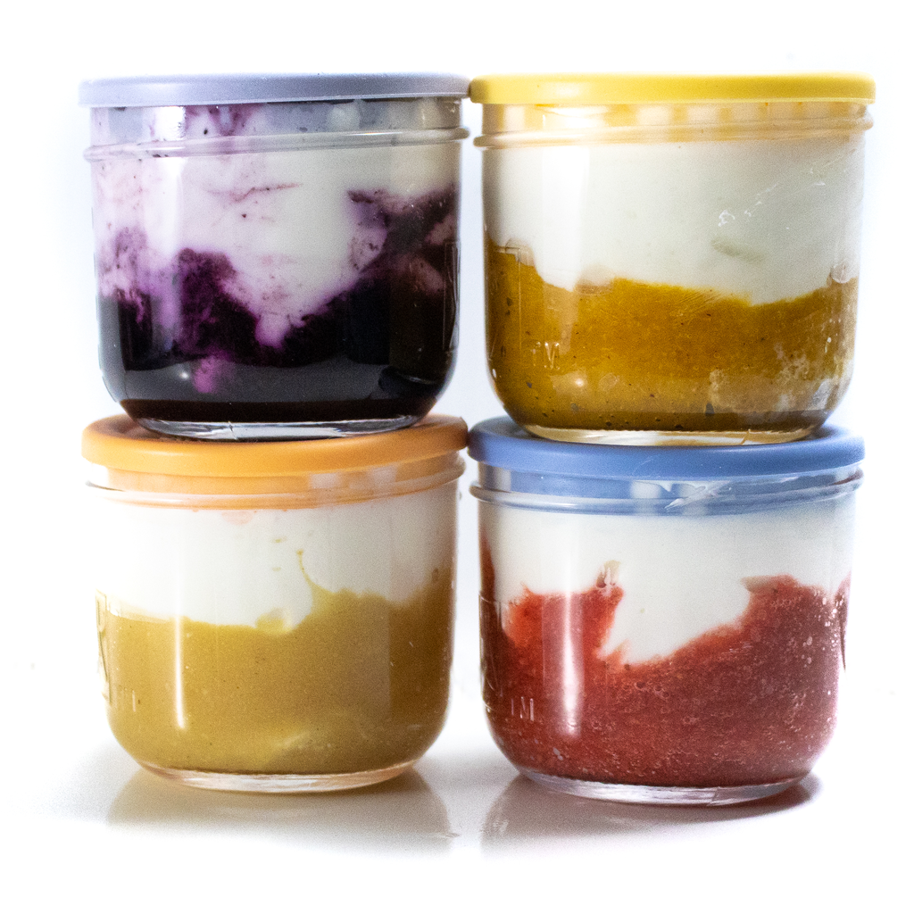 四个不同的透明罐的侧面视图，底部有果实，顶部有彩色的盖子。