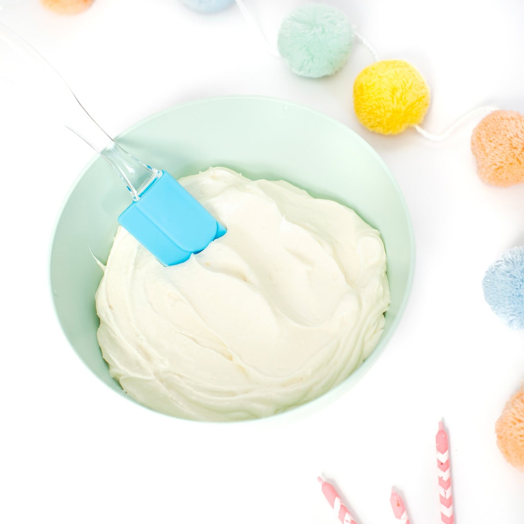 蓝绿色的绿色儿童碗碗充满了光滑健康的糖霜，并在白色背景上装满了一些五颜六色的派对道具。