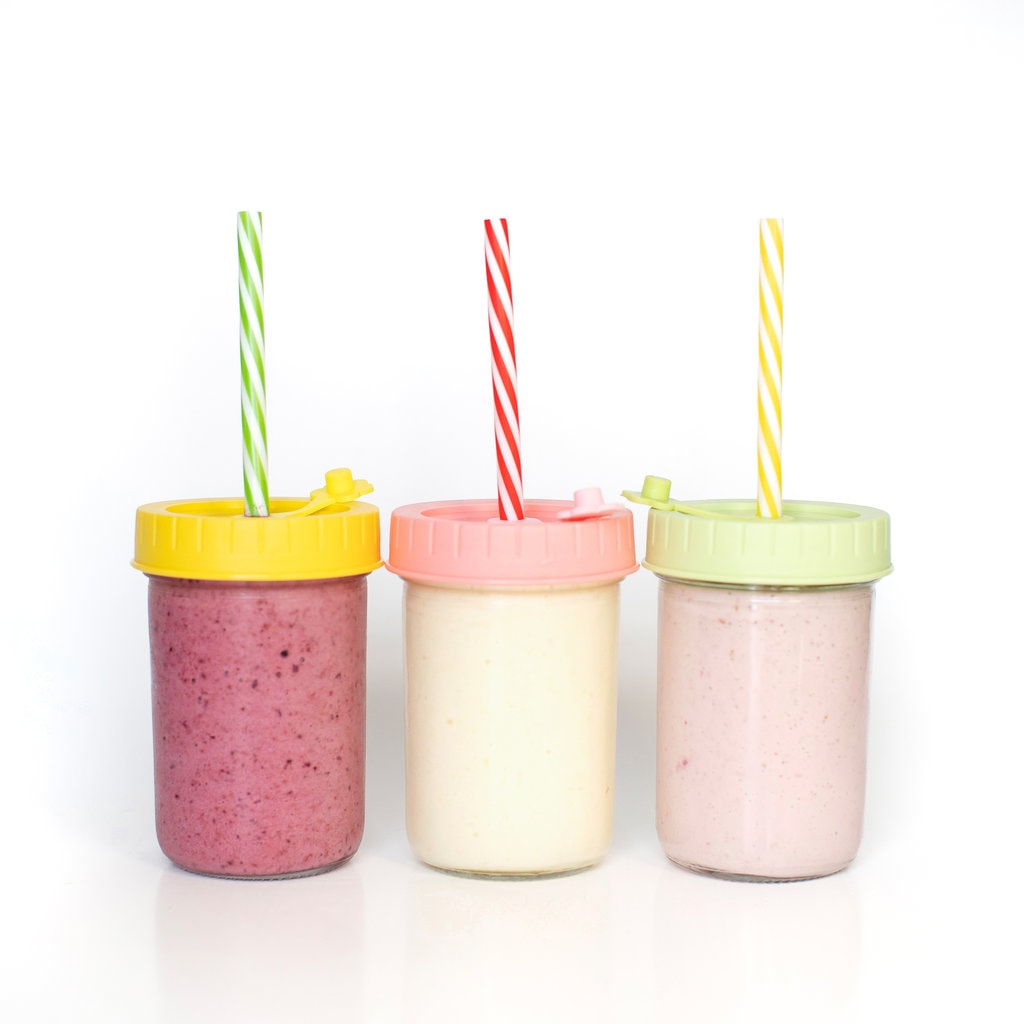 可欣赏三个玻璃罐，上面有五颜六色的盖子和为儿童提供酸奶饮料的吸管。