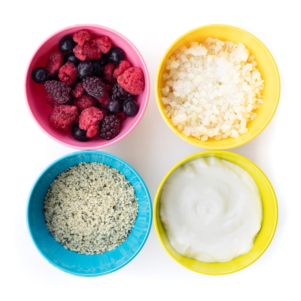 四色五颜六色的孩子碗，里面装满了酸奶饮料的健康成分。