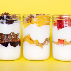 三个玻璃罐装满了水果充满酸奶冻糕的孩子，适合在黄色背景下有很多水果和健康浇头的孩子。