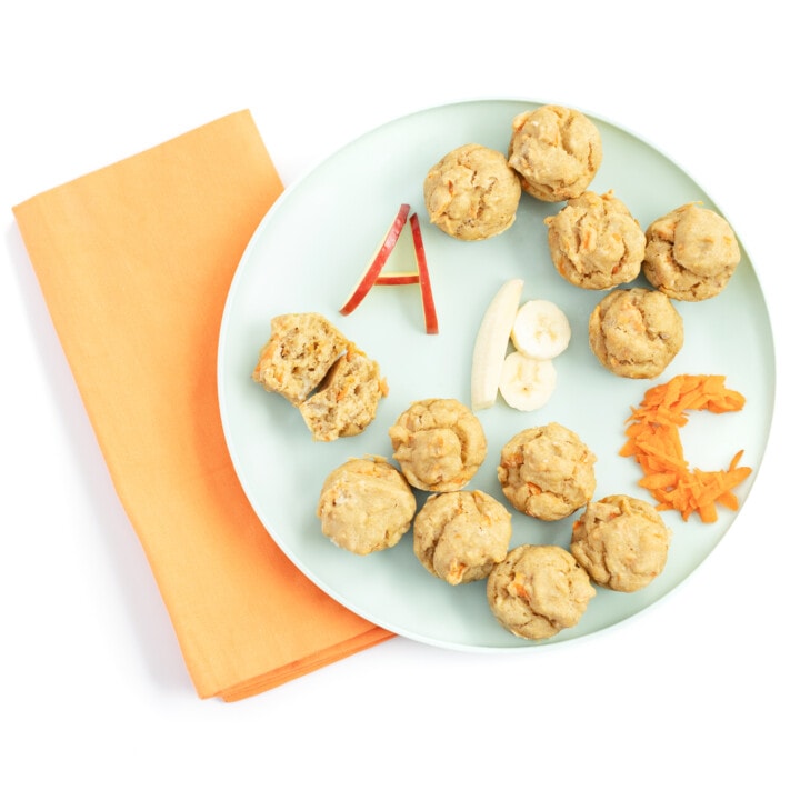 蓝绿色的孩子与ABC松饼一起玩，用字母A，B，C用苹果，香蕉和胡萝卜写出来，并用橙色的餐巾纸说大理石背景。