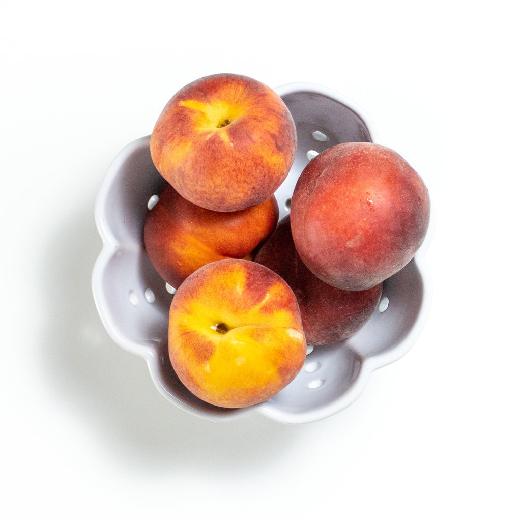 碗在碗中的桃子在白色背景上。GydF4y2Ba