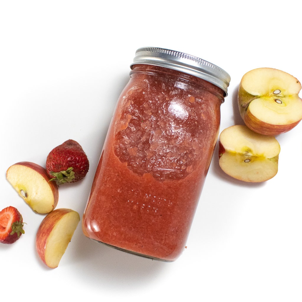一个带草莓苹果酱的类罐子，上面有草莓和苹果，围绕着客观的背景散布着。GydF4y2Ba