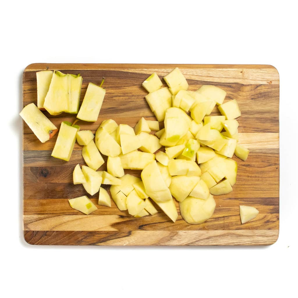 一个木制切菜板，上面有切碎的苹果在白色背景上。GydF4y2Ba