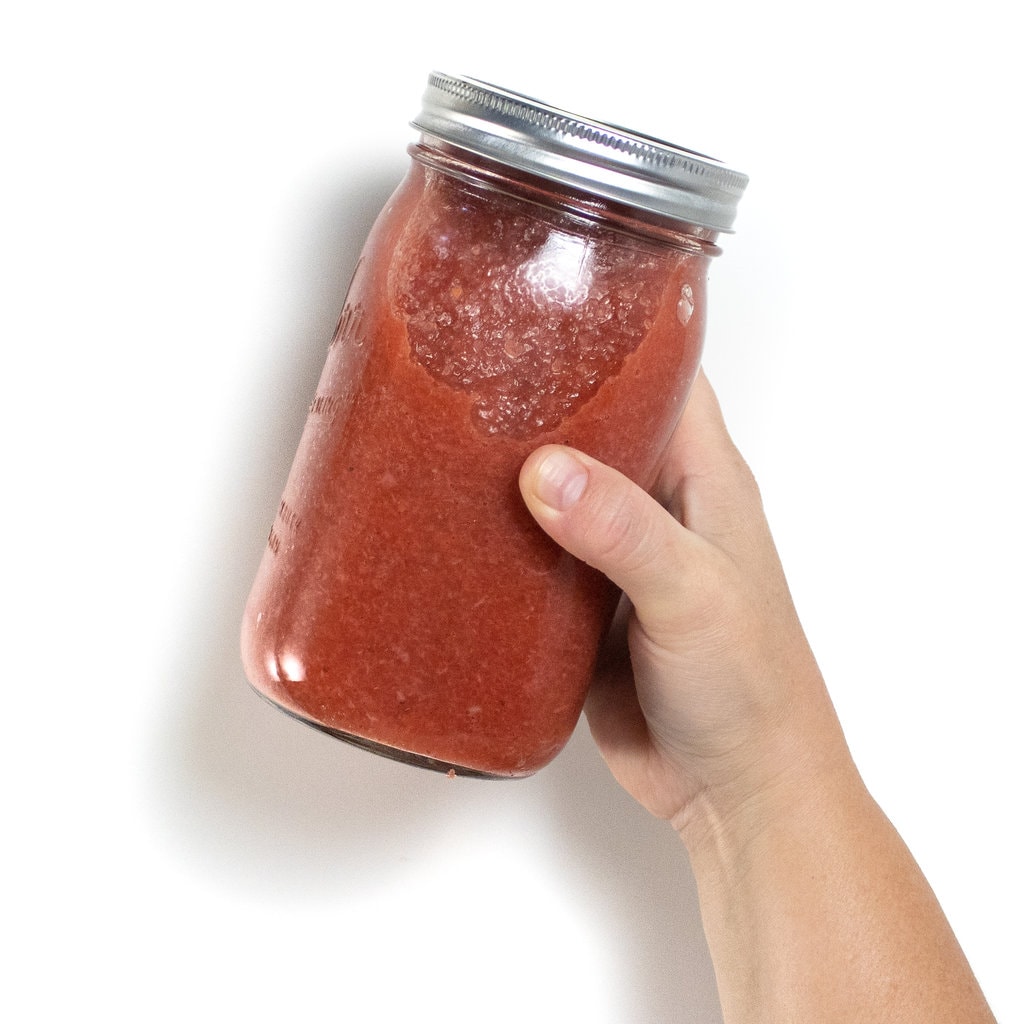一罐草莓苹果酱手工靠在白色背景上。GydF4y2Ba
