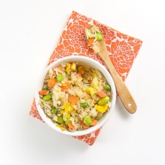 白碗装满棕米、蔬菜和大片炒鸡蛋白碗坐在橙色餐巾上并加花