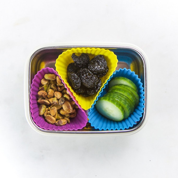 矩形小朋友盒和健康小吃-3松饼模子填满pistachios、干果和割黄瓜