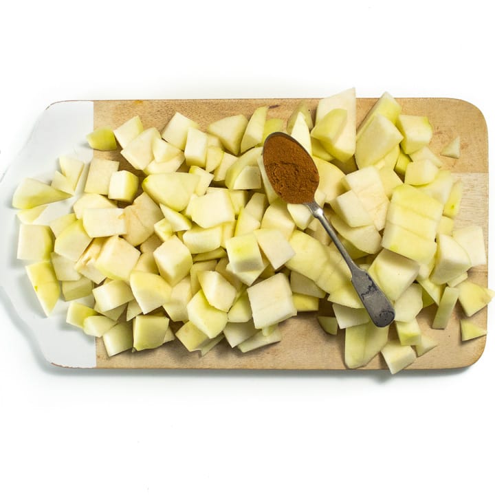 切碎的梨在切菜板上，上面放着一汤匙香料。