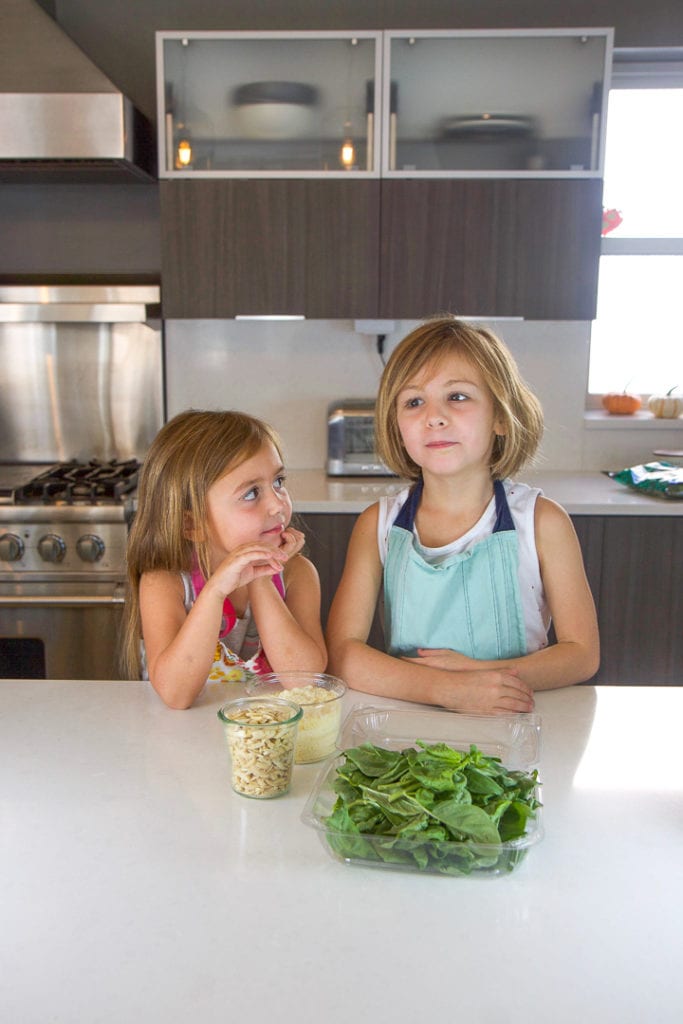 与孩子一起做饭-2个女孩站在厨房柜台上,前面传播食谱素材