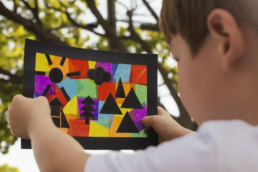 孩子举着五颜六色的拼贴画。