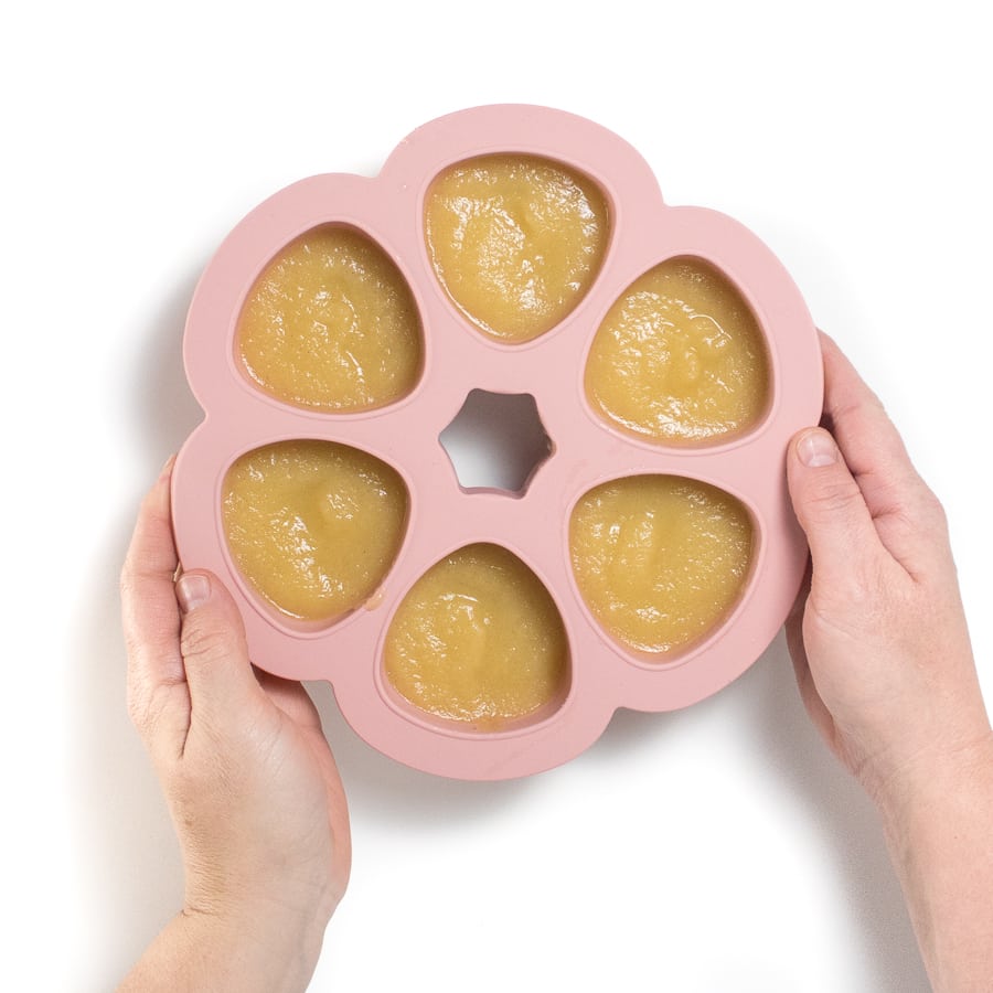 粉色婴儿食品容器加净苹果和手握
