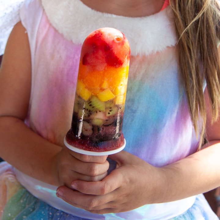 年轻姑娘穿彩虹洋装 握着彩虹冰棒