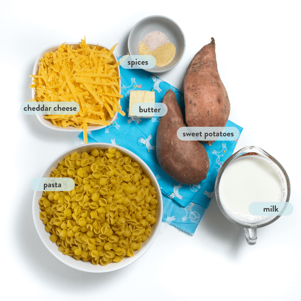 Spread of ingredients for sweet potato mac & cheese labeled with their names against a white background on top of a blue napkin.