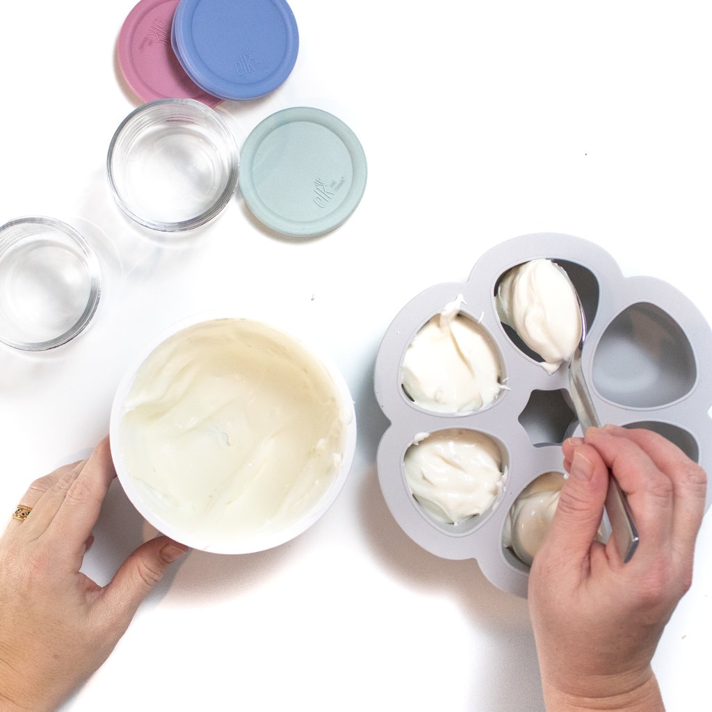 双手勺白酸奶散入装有玻璃容器的冰盒,盖子贴近白后台