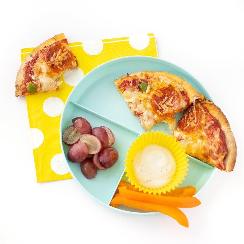 儿童区块比萨加番茄加葡萄,黄餐巾顶上带部分披萨并咬出