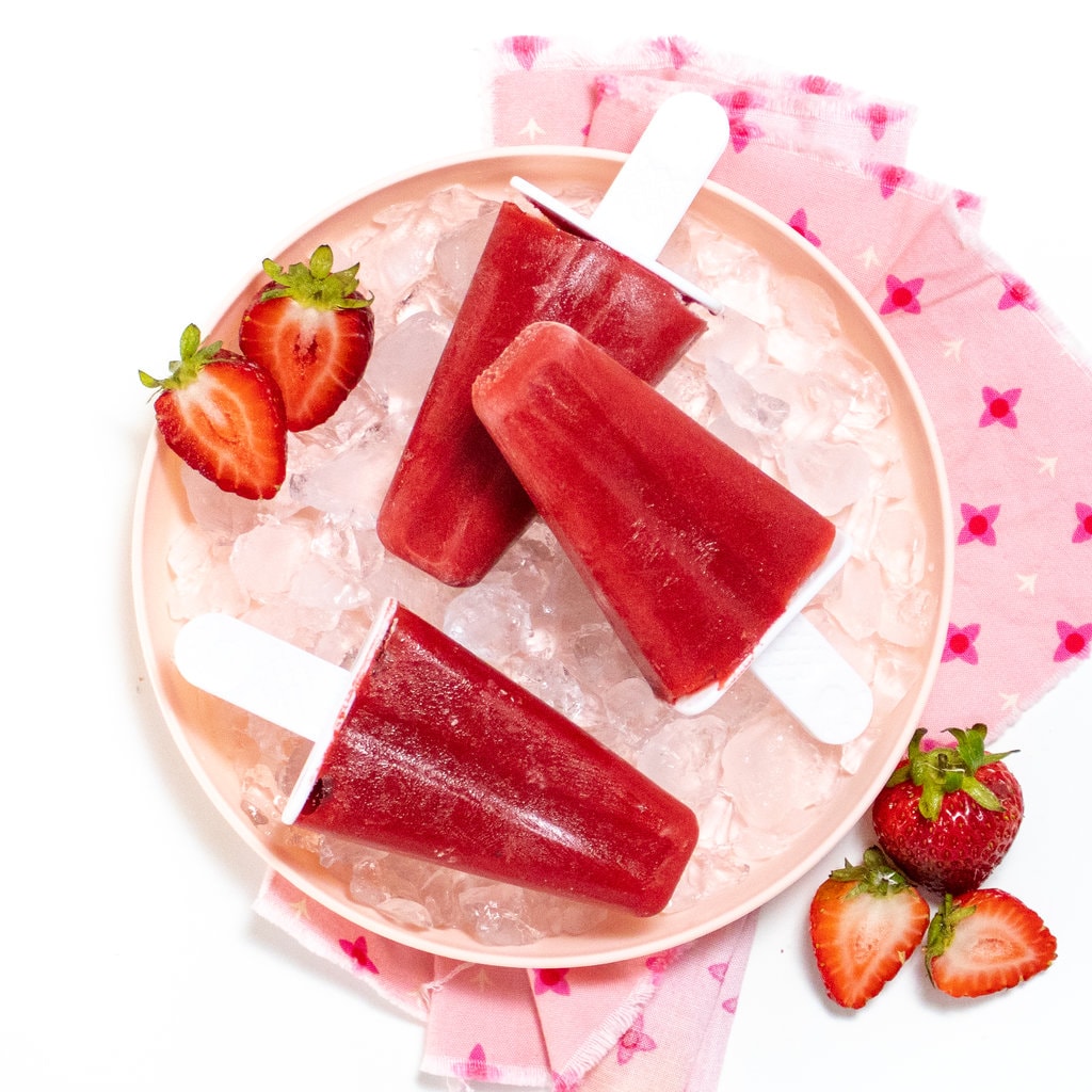 粉色小朋友板块加冰块和三片草莓冰块,边边贴草莓贴白背景粉红色餐巾